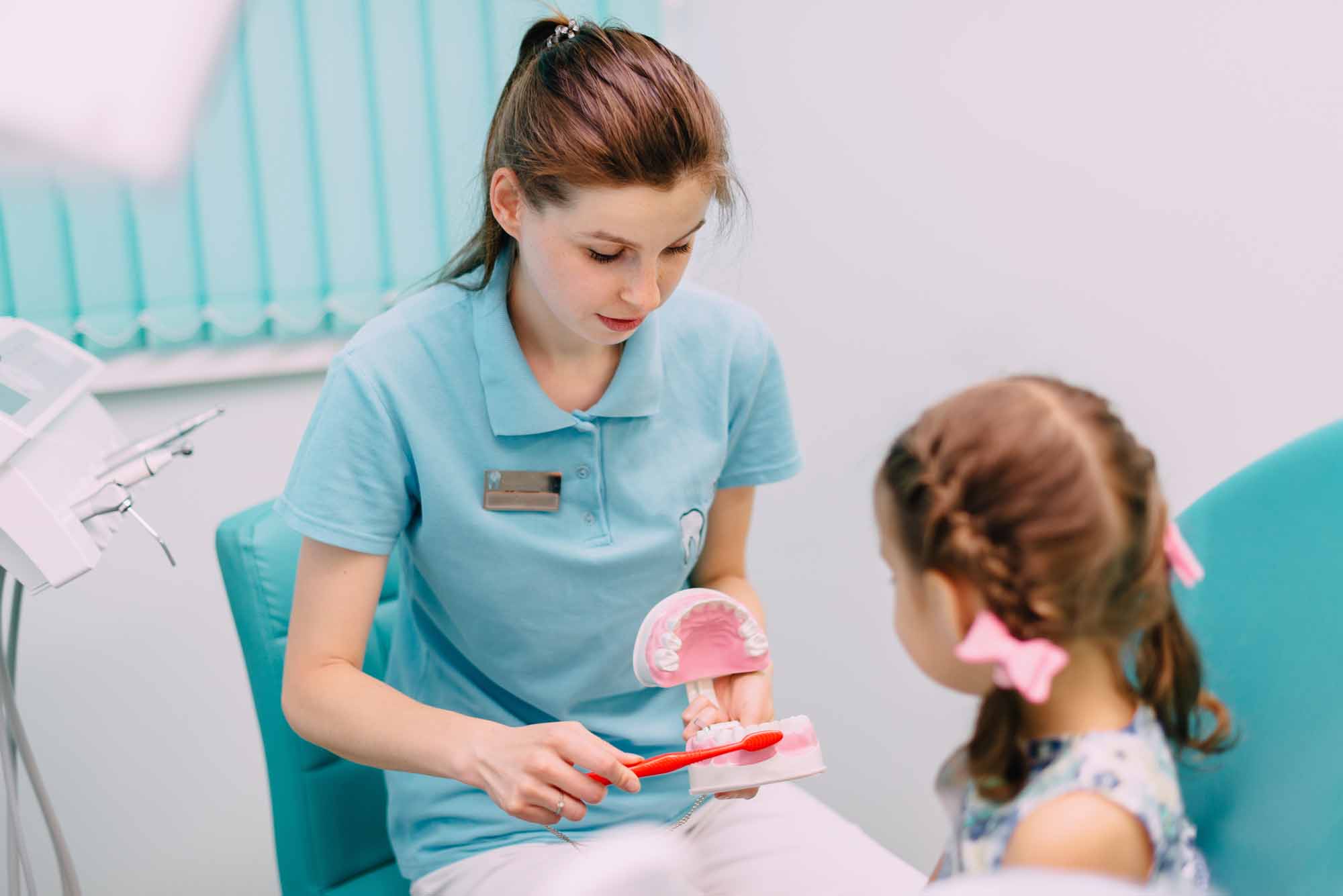 Pediatric dentist showing young girl how to brush her teeth - Smart Pediatric Dentistry, Utah